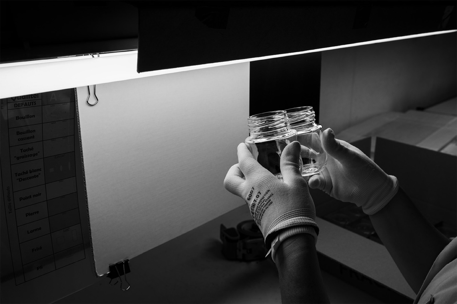 Glass jars held up for inspection at a vision station