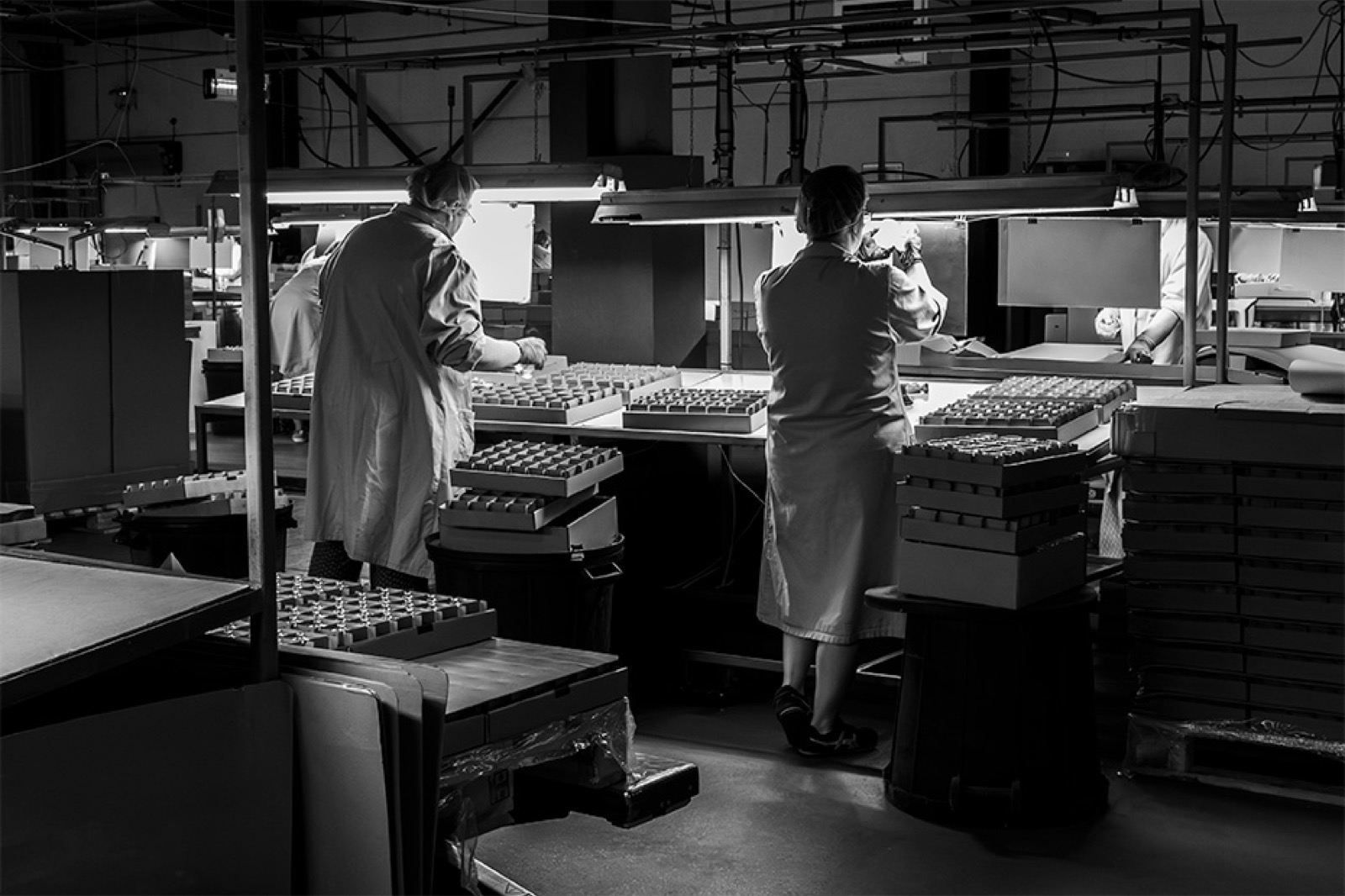 Deux opératrices au tri, plateaux de flacons de part et d'autre du poste